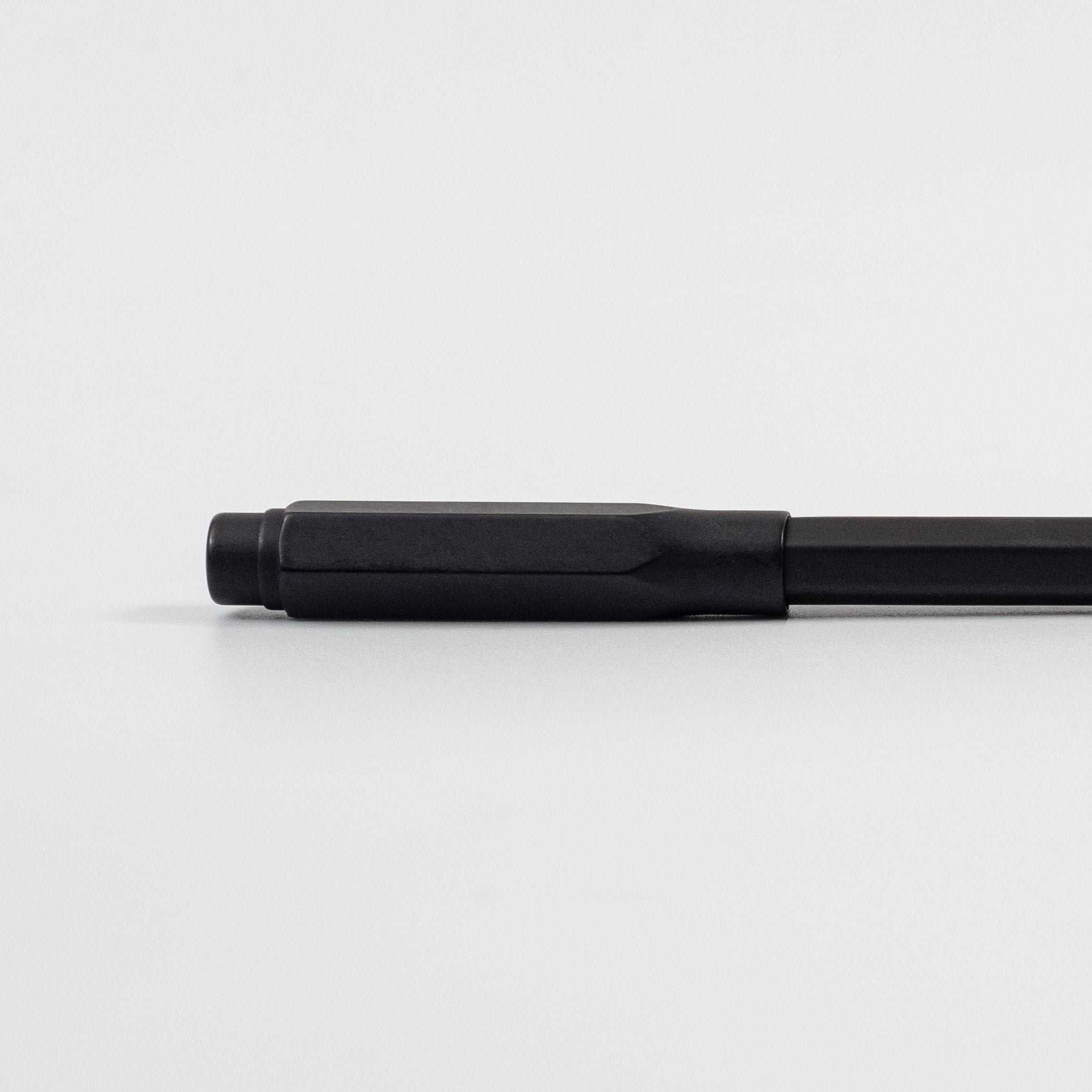 A black, gold, and silver Blackwing Point Guard sits on a white surface next to a Blackwing pencil.