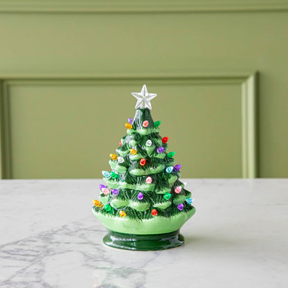 An 8&quot; Porcelain Vintage Lit Tree with Timer on a marble table.