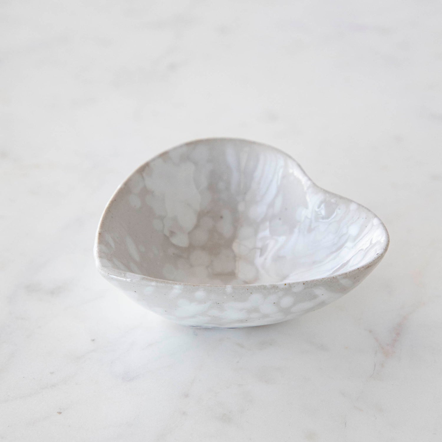 A small Stoneware Heart Dish by Creative Co-Op on a marble table.