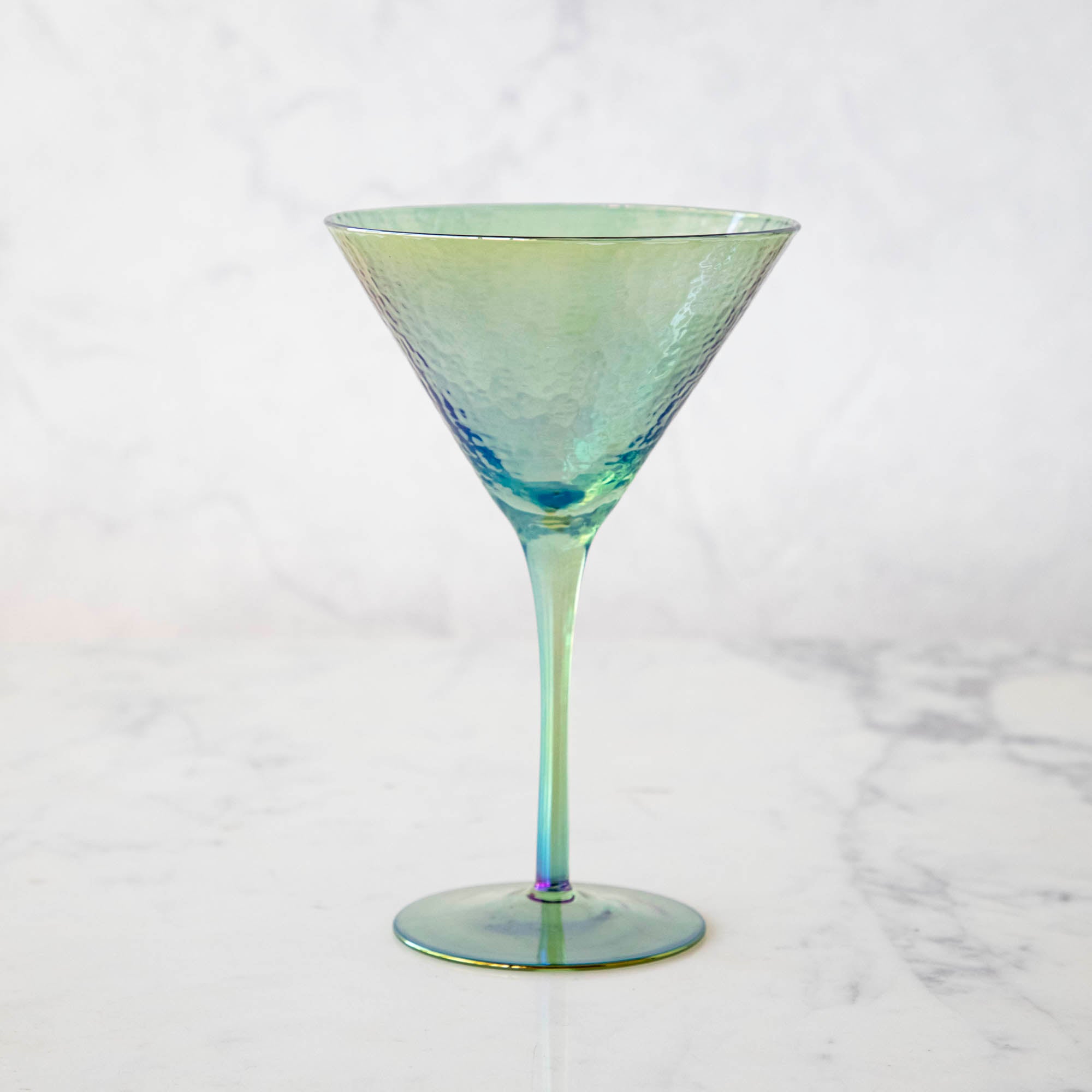 Four stylish Luster Aperitivo Martini Glasses in Zodax with sugar rims on a white stand against a marble background.