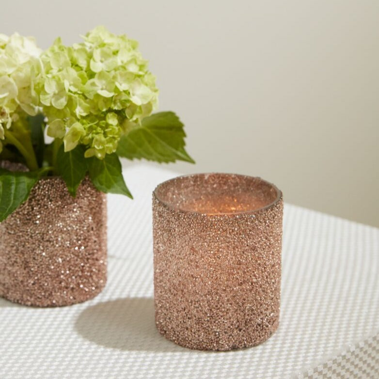 One Pink Shimmer Votive with flowers in it and another with a lit candle.