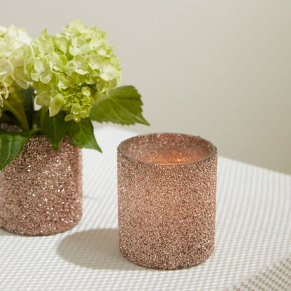 One Pink Shimmer Votive with flowers in it and another with a lit candle.