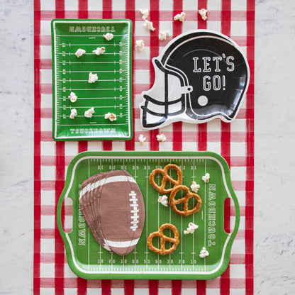 Football themed paper plates with various snacks on a red painted check runner.