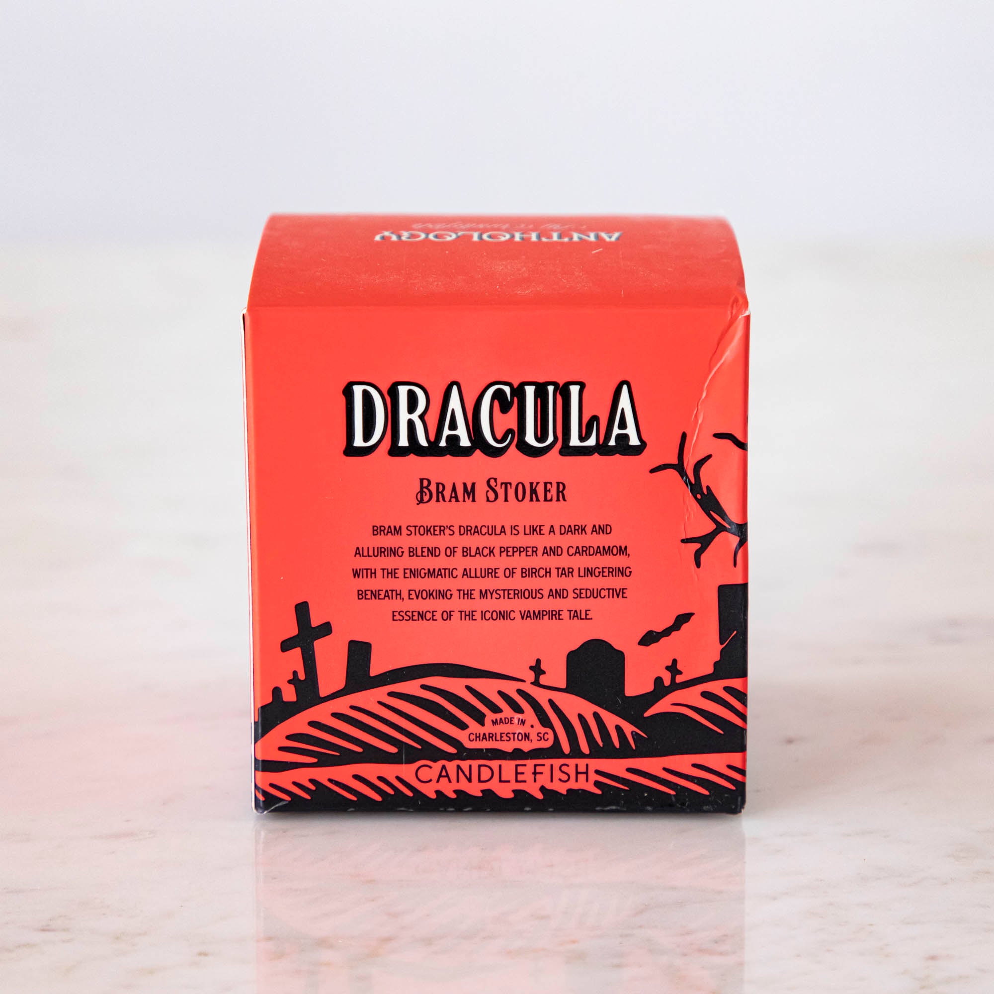 A Dracula themed candle box with a red background and black silhouettes, inspired by Bram Stoker.