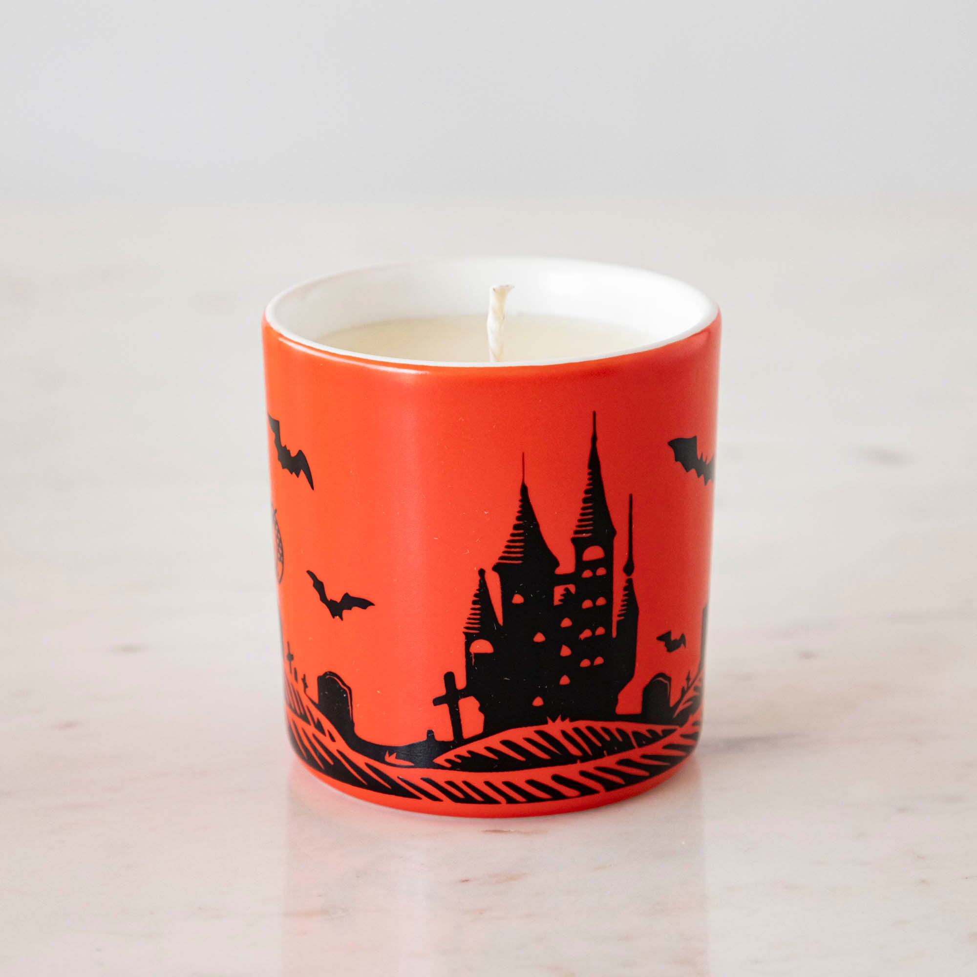 A Dracula themed candle with a red background and black silhouettes.