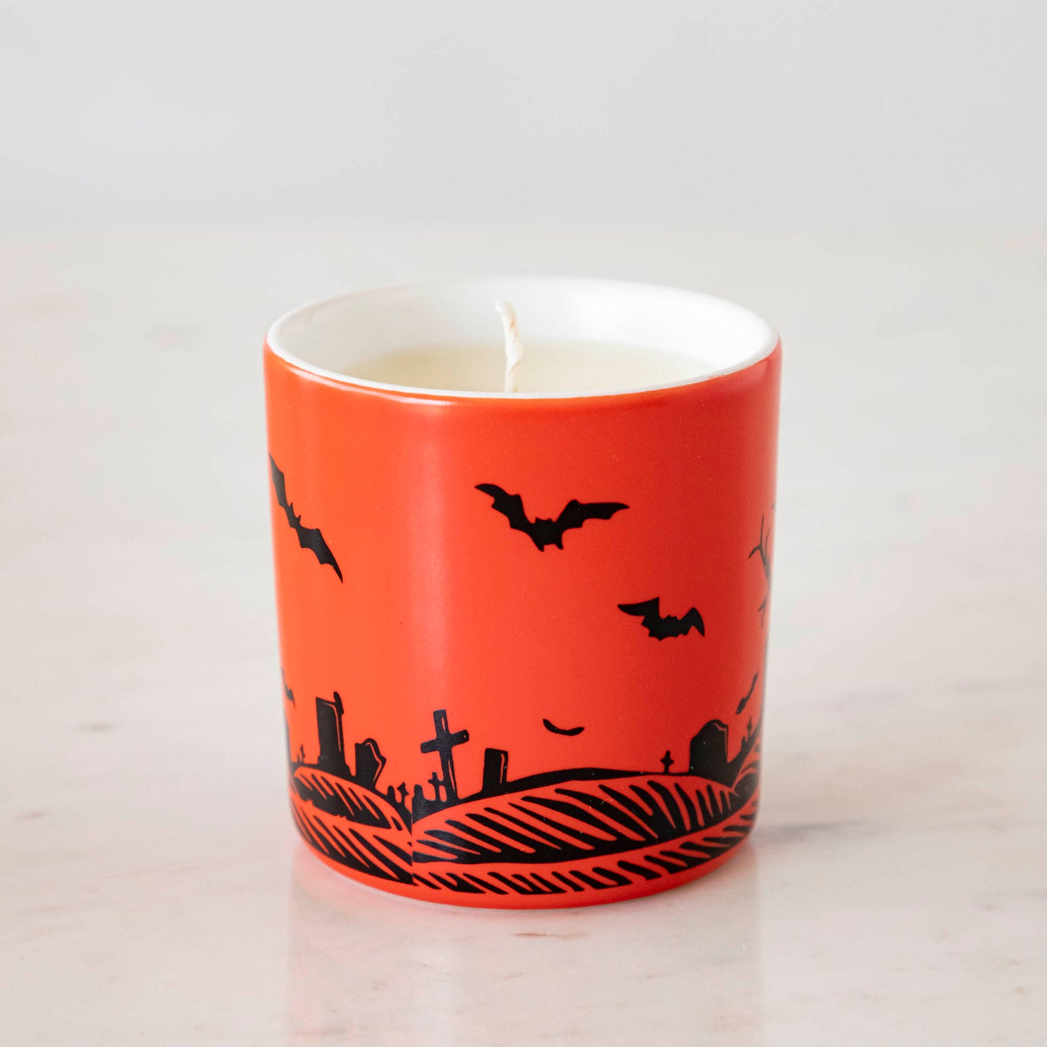 A Dracula themed candle with a red background and black silhouettes.