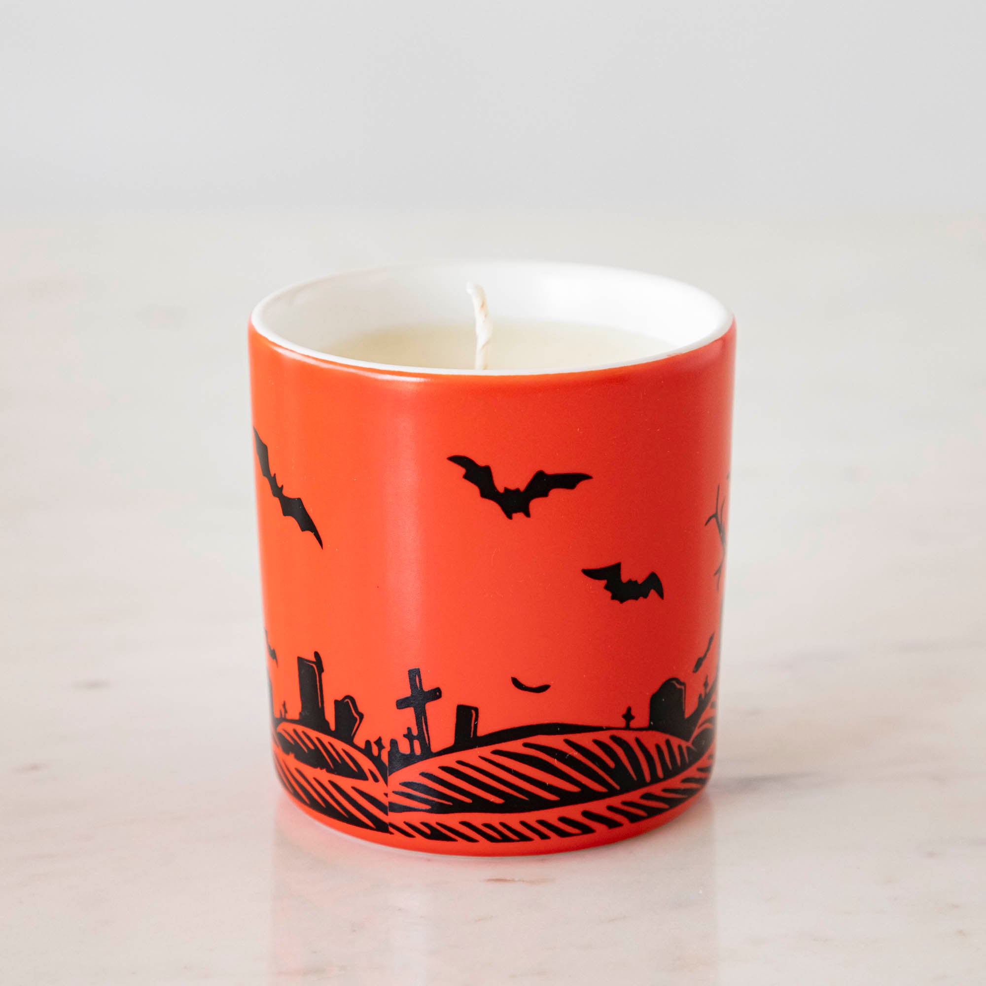 A Dracula themed candle with a red background and black silhouettes.