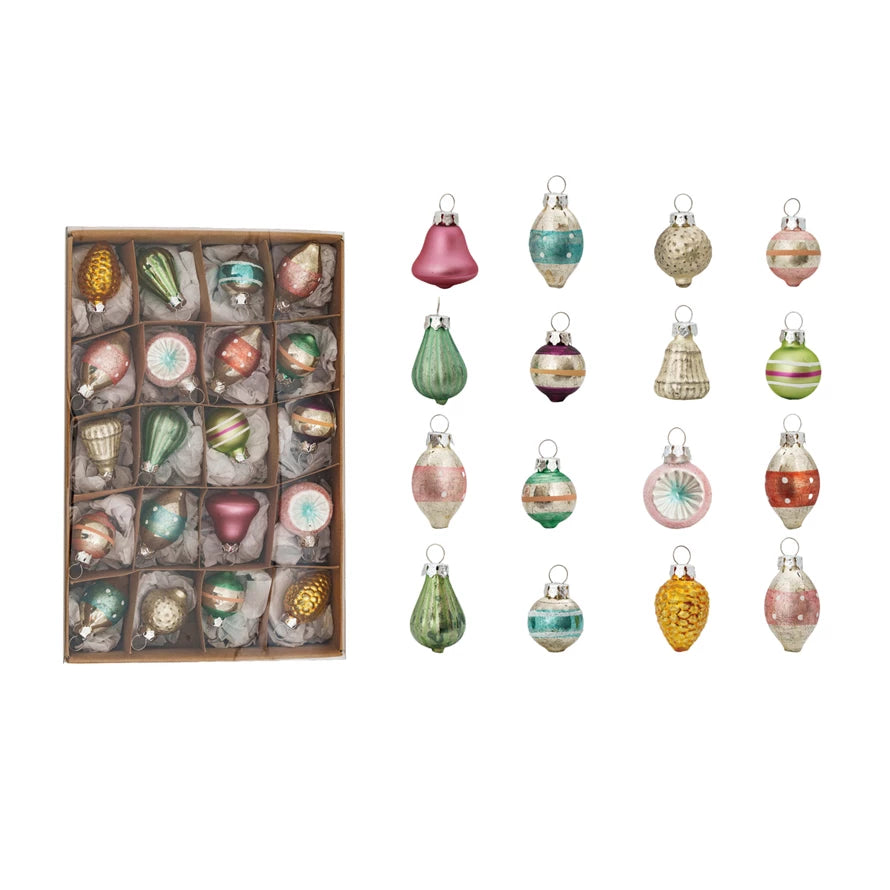 A box of assorted vintage inspired pastel ornaments in a box and out of the box, on a white background.