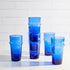 A set of blue Kiss That Frog Beldi glass tumblers on a white table.