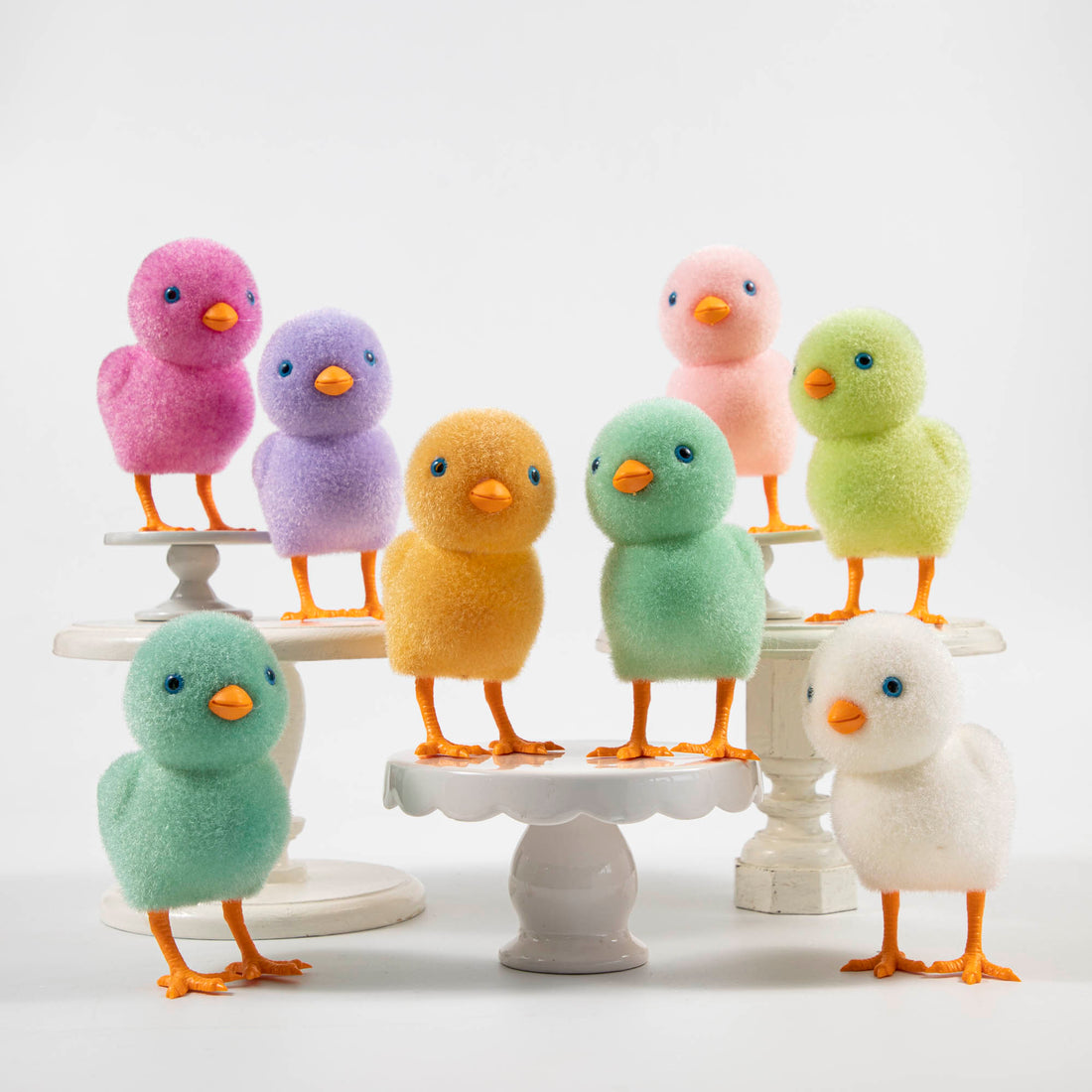 A group of colorful Glitterville felt chicks on a white plate, ready for the Easter celebration.