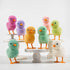 A group of colorful Glitterville felt chicks on a white plate, ready for the Easter celebration.