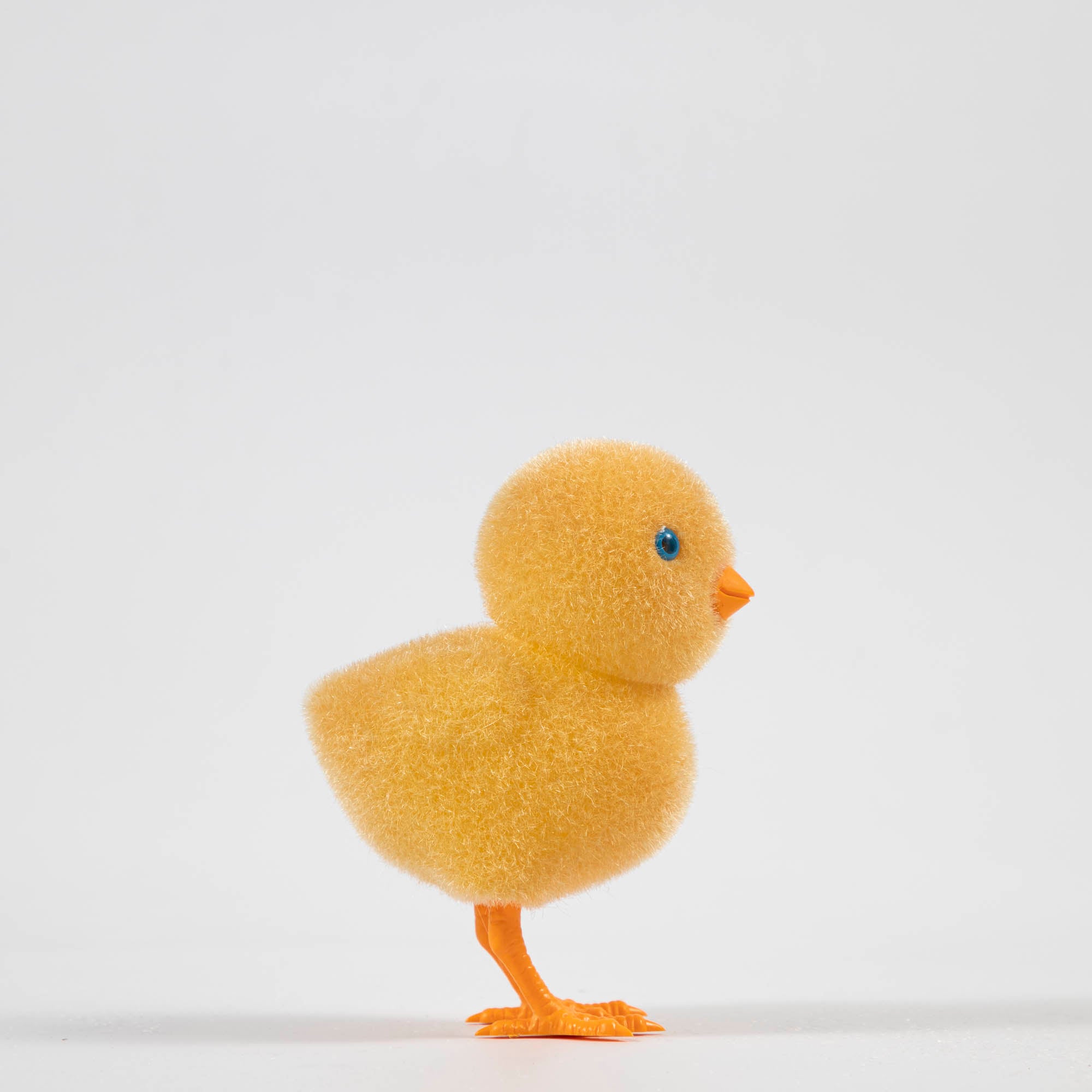 A group of colorful Glitterville felt chicks on a white plate, ready for the Easter celebration.