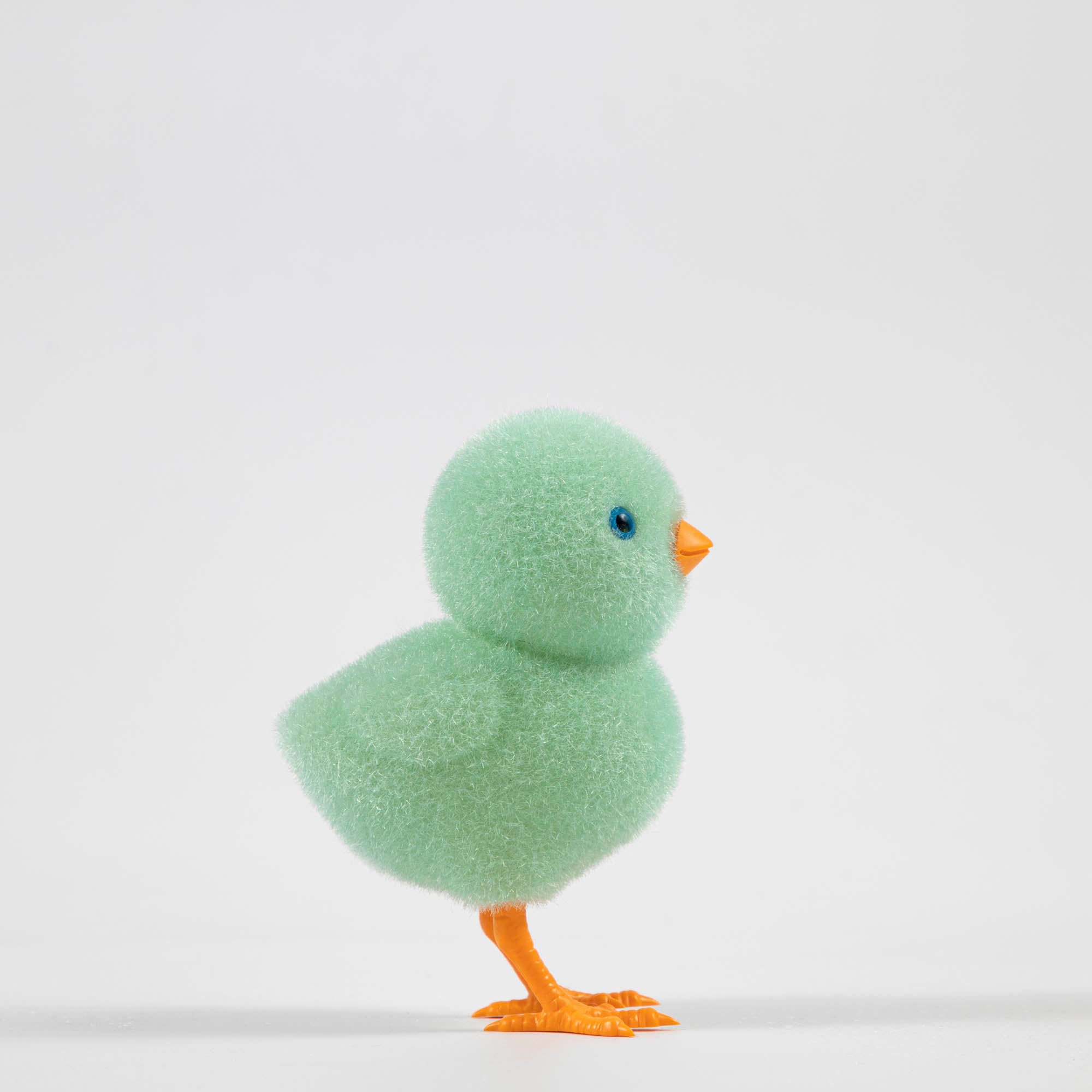 A group of colorful Glitterville felt chicks on a white plate, ready for the Easter celebration.