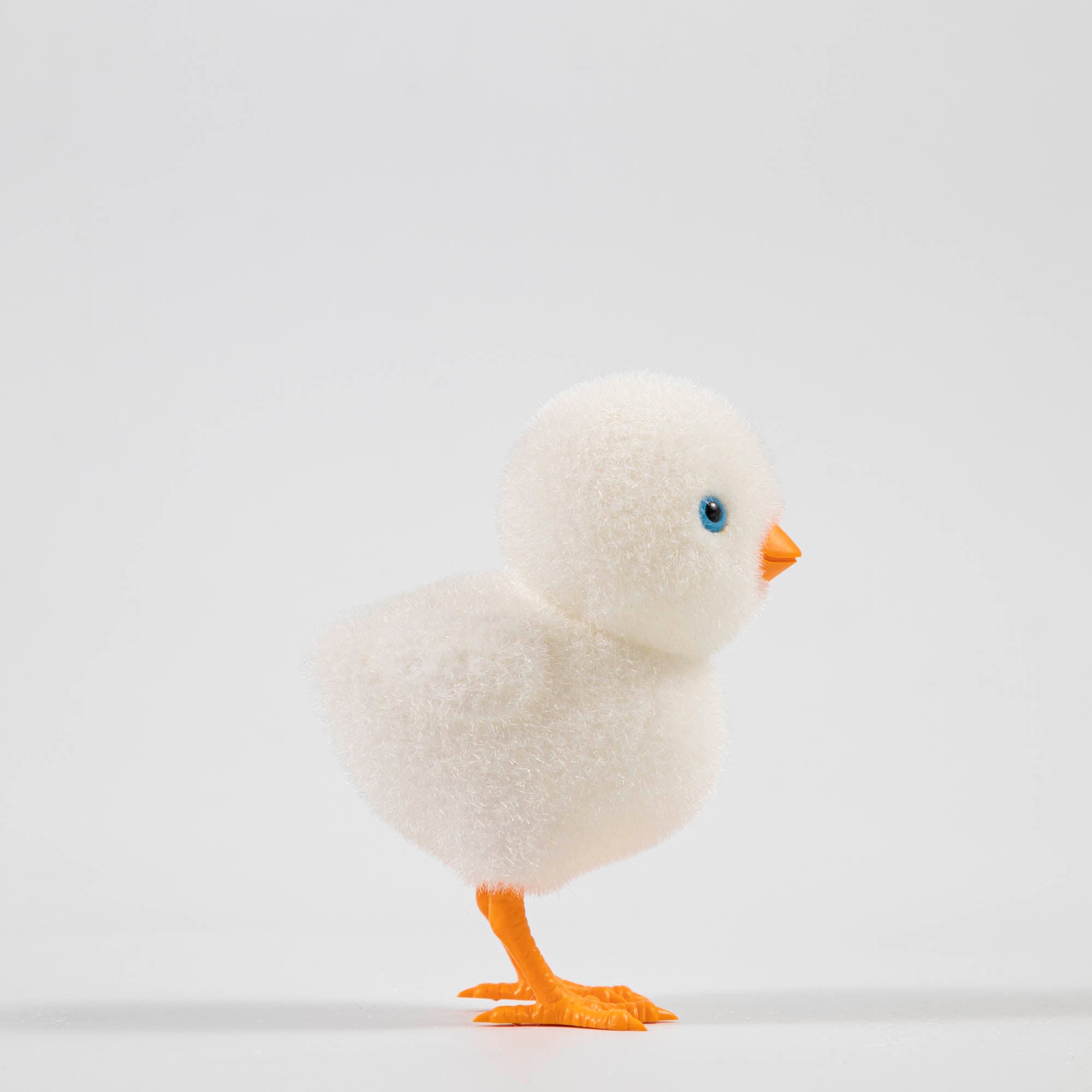 A group of colorful Glitterville felt chicks on a white plate, ready for the Easter celebration.