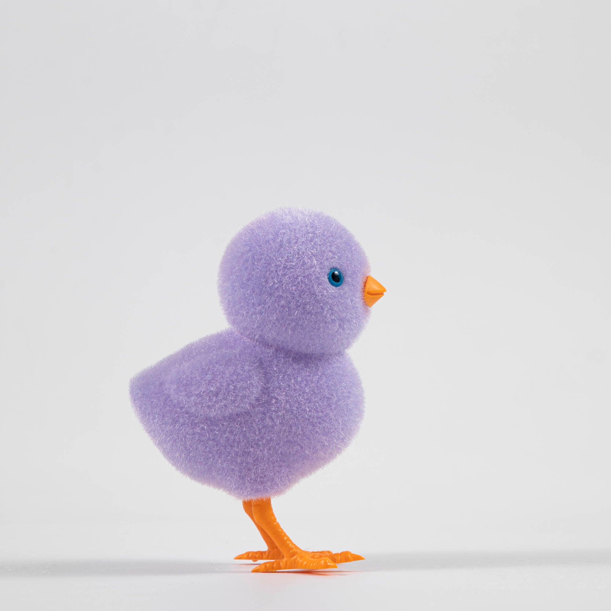 A group of colorful Glitterville felt chicks on a white plate, ready for the Easter celebration.