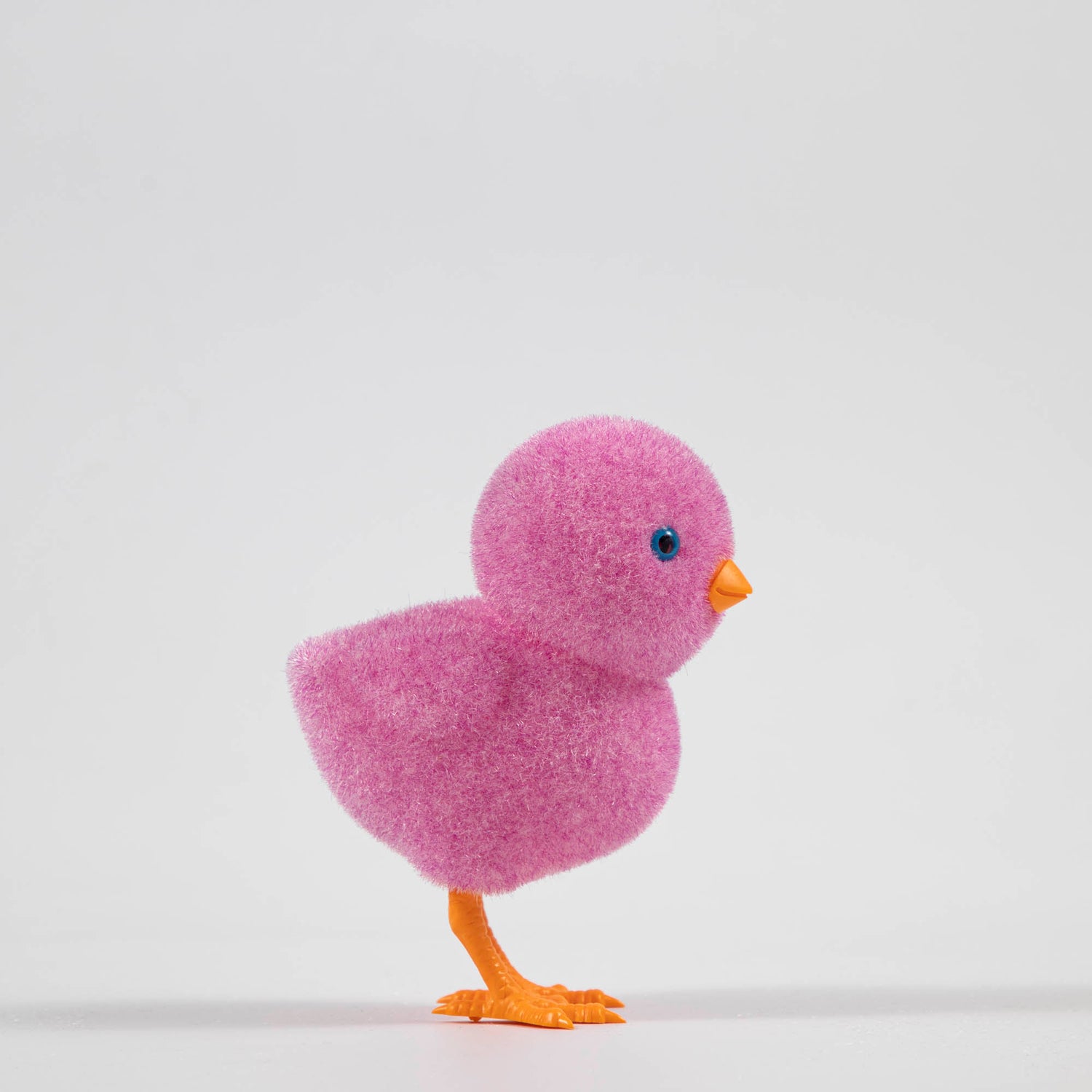 A group of colorful Glitterville felt chicks on a white plate, ready for the Easter celebration.