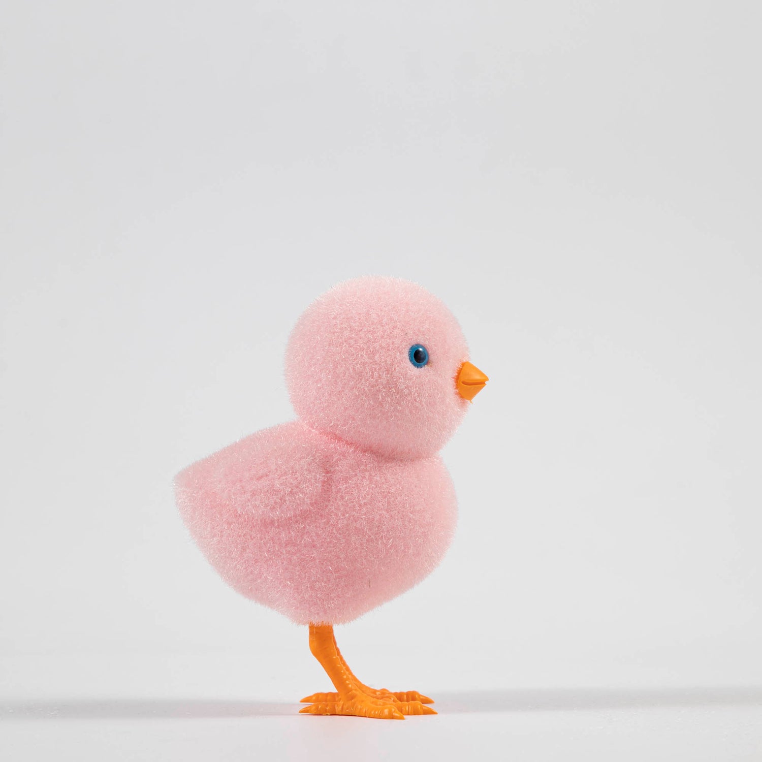 A group of colorful Glitterville felt chicks on a white plate, ready for the Easter celebration.