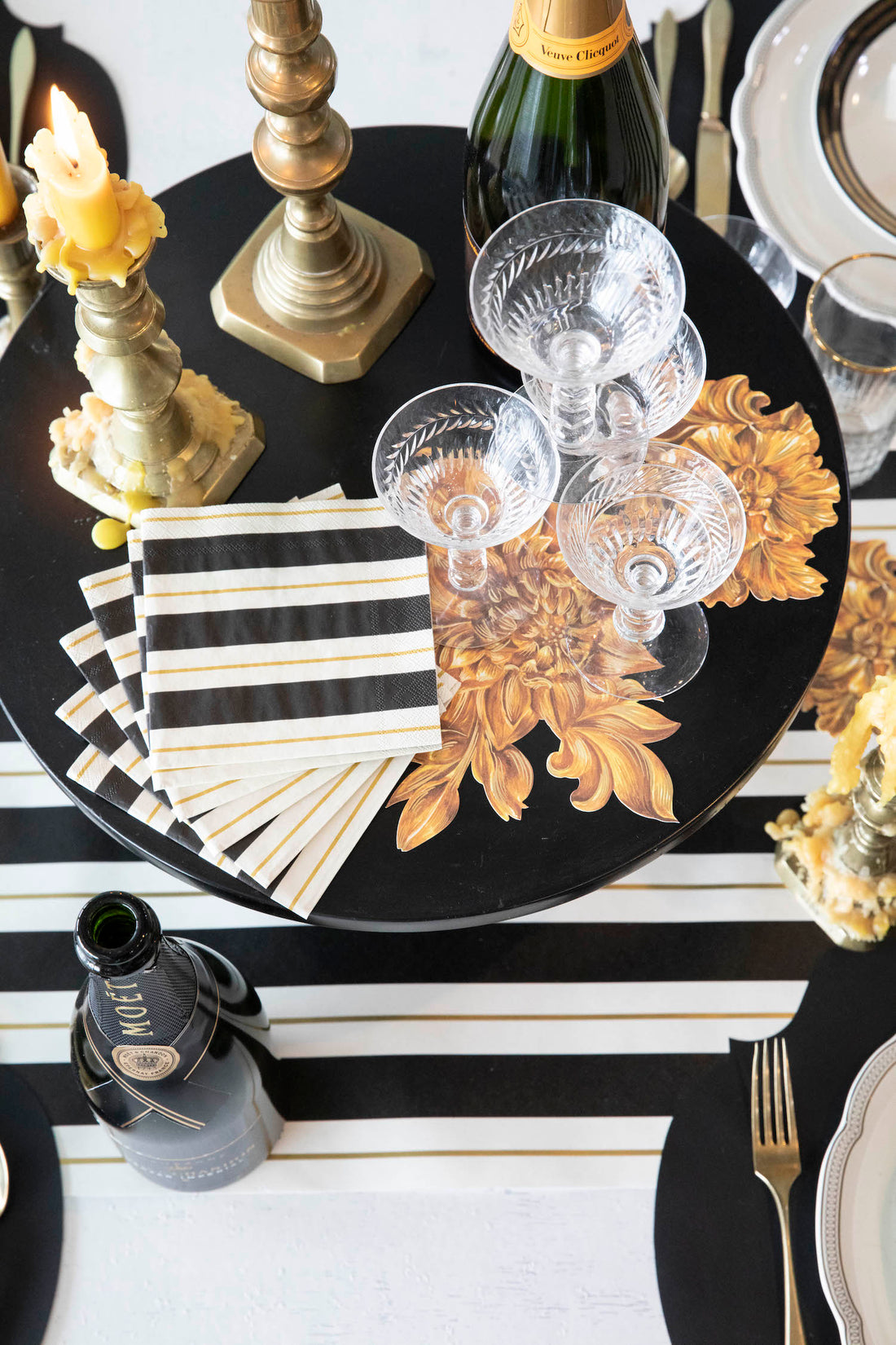 A stack of Black &amp; Gold Awning Stripe Cocktail Napkins fanned out on an elegant tablescape.