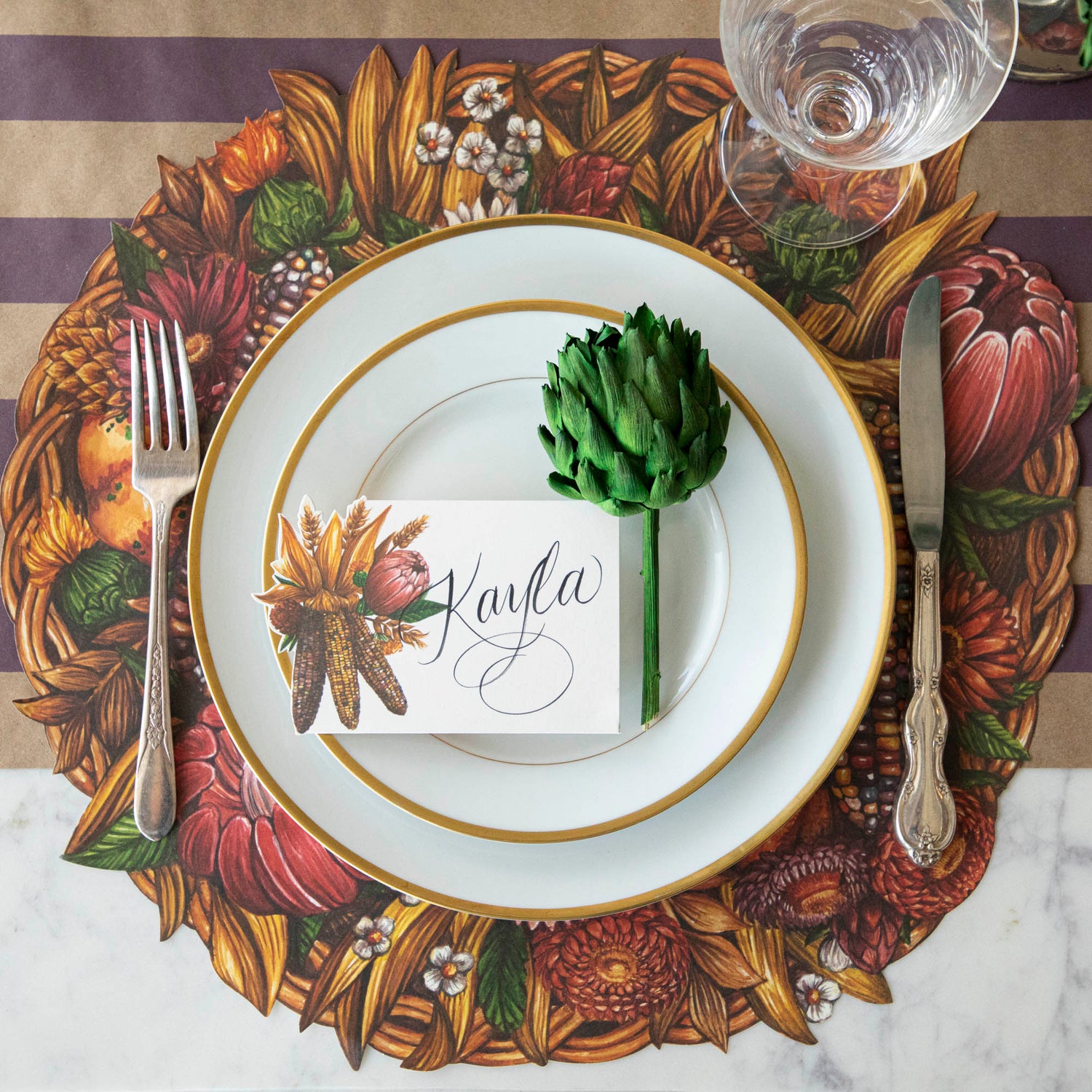 Place setting with a single dried green artichoke on the plate next to a place card