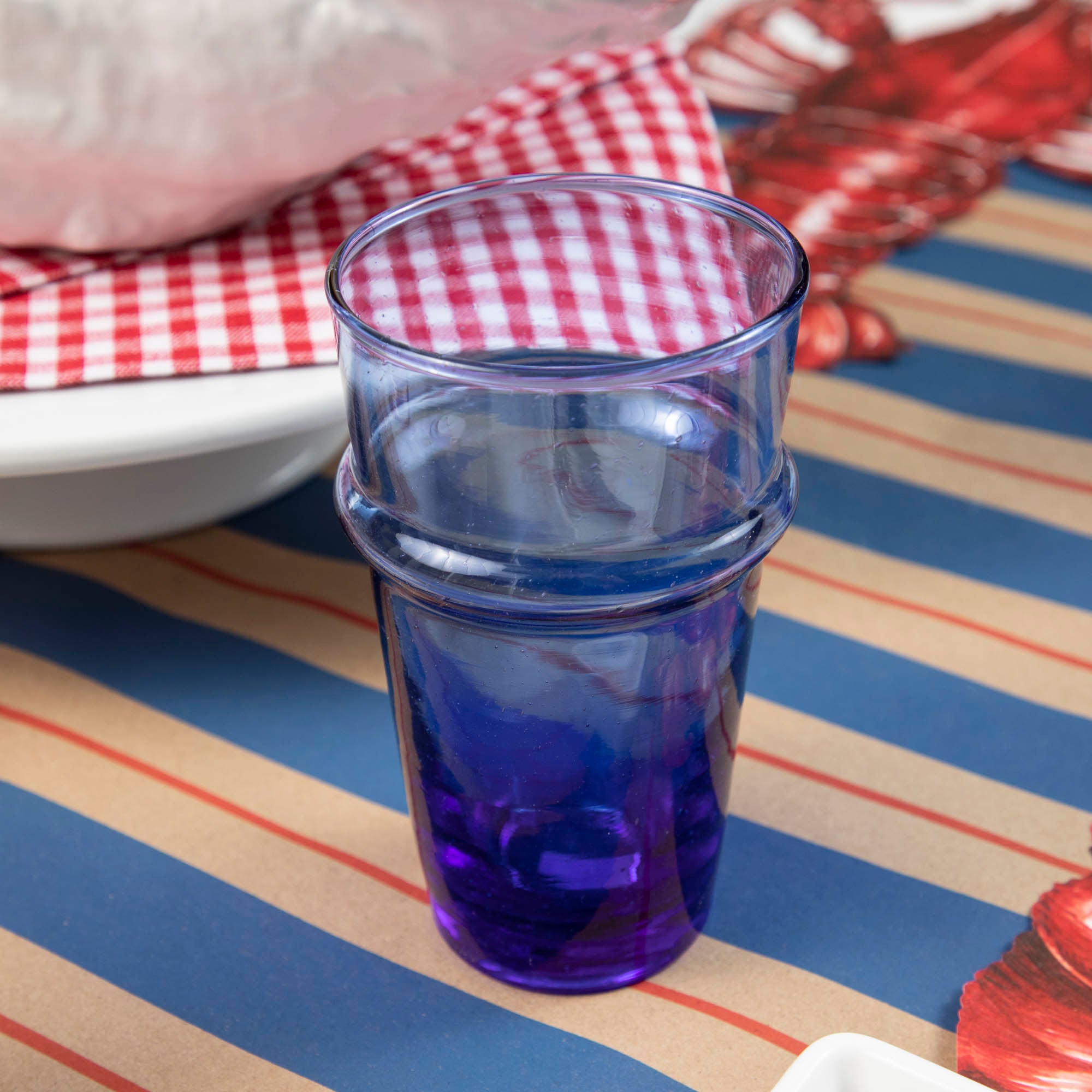 A set of blue Kiss That Frog Beldi glass tumblers on a white table.