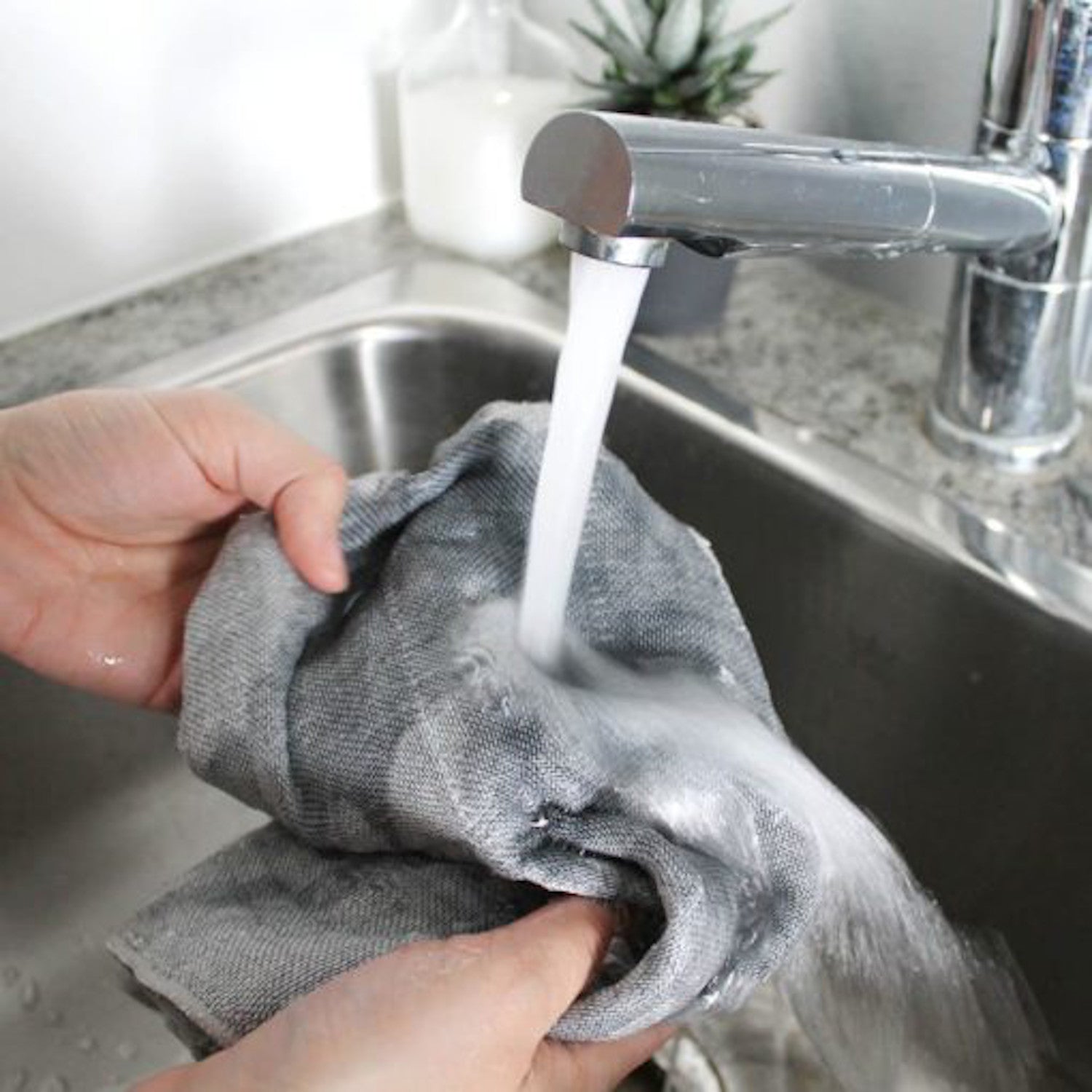 A person washing an Ippinka Binchotan Dishcloth in a sink, following Japanese tradition.