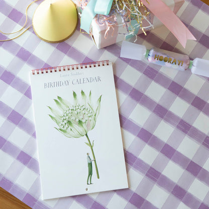 The Laura Stoddart Birthday Calendar resting on a festive table decorated for a party.