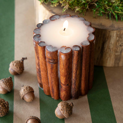 A topdown view of the Cinnamon Stick Scented Pillar Candle lit up, showing the detailed Cinnamon Stick bound together with wax.