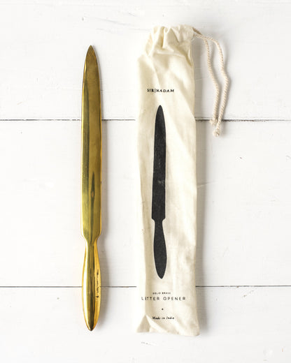 brass letter opener next to muslin package it comes in