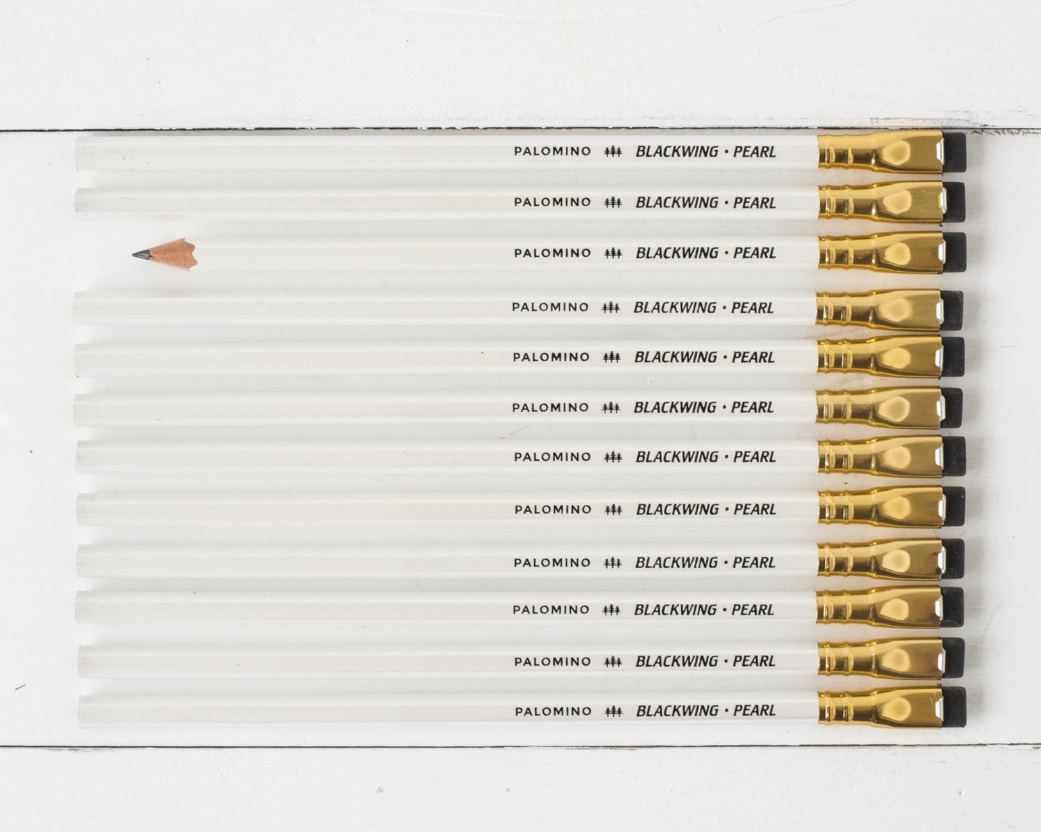 A Blackwing Pearl Pencils Set of 12 with a graphite core and white eraser next to its packaging box on a white background.