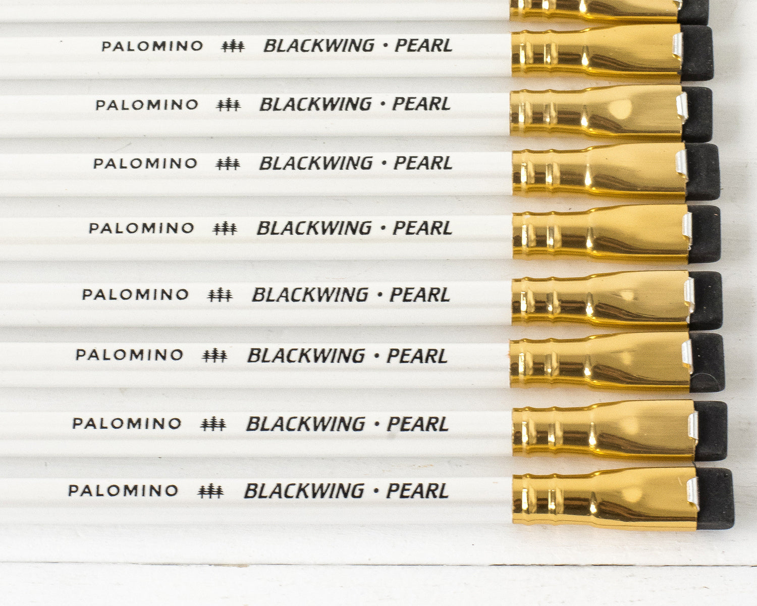 A Blackwing Pearl Pencils Set of 12 with a graphite core and white eraser next to its packaging box on a white background.