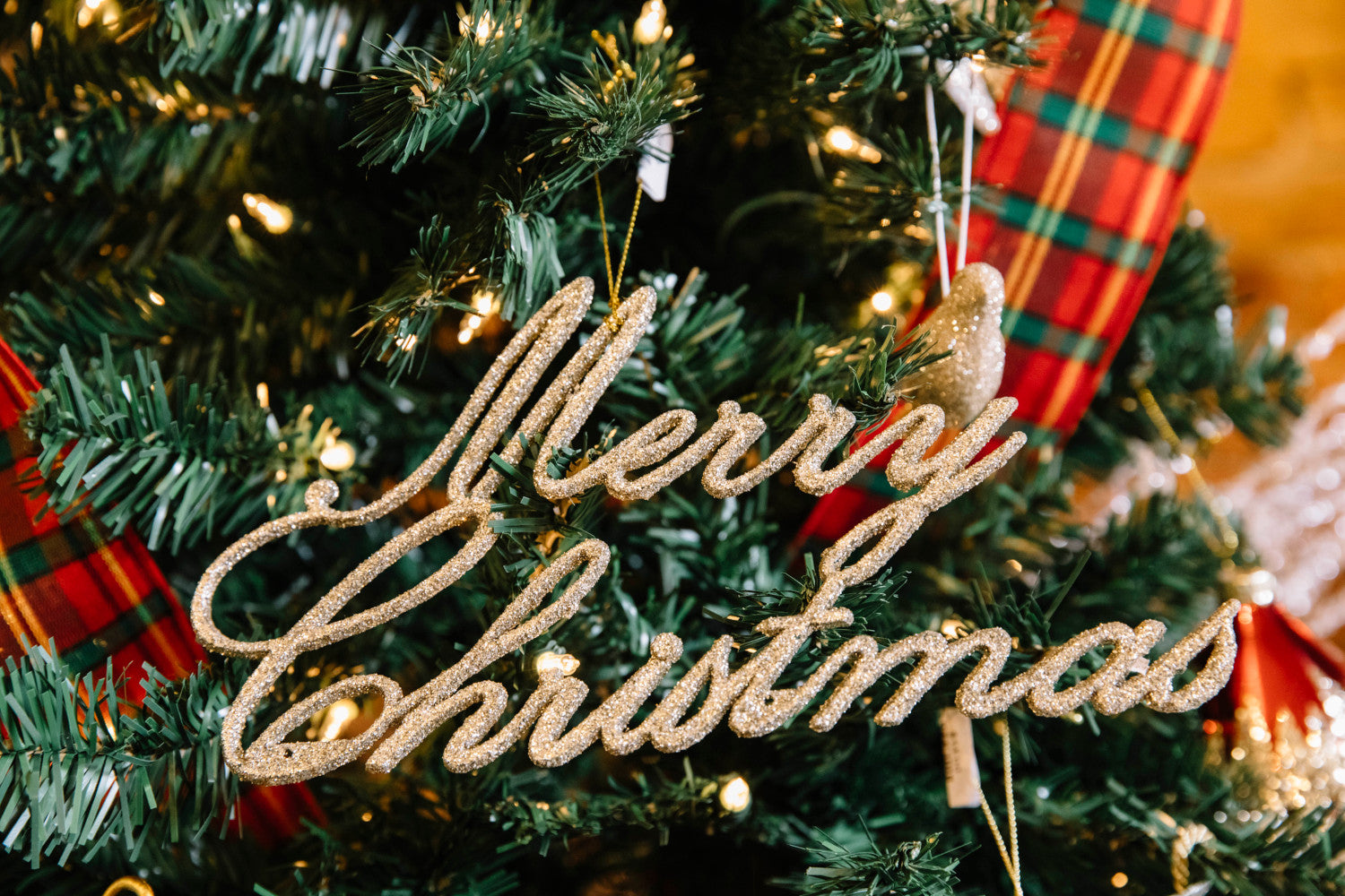 Champagne Merry Christmas Ornament hanging in a tree.