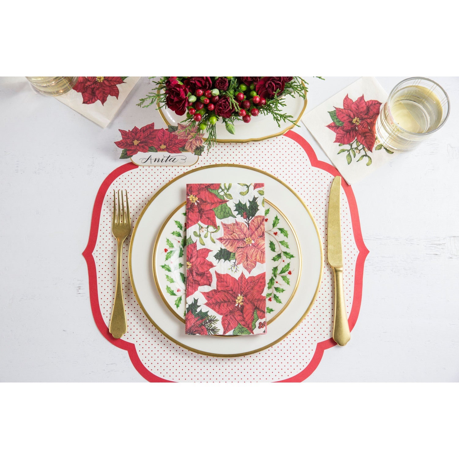 A festive Christmas place setting featuring a Poinsettia Guest Napkin centered on the plate, from above.