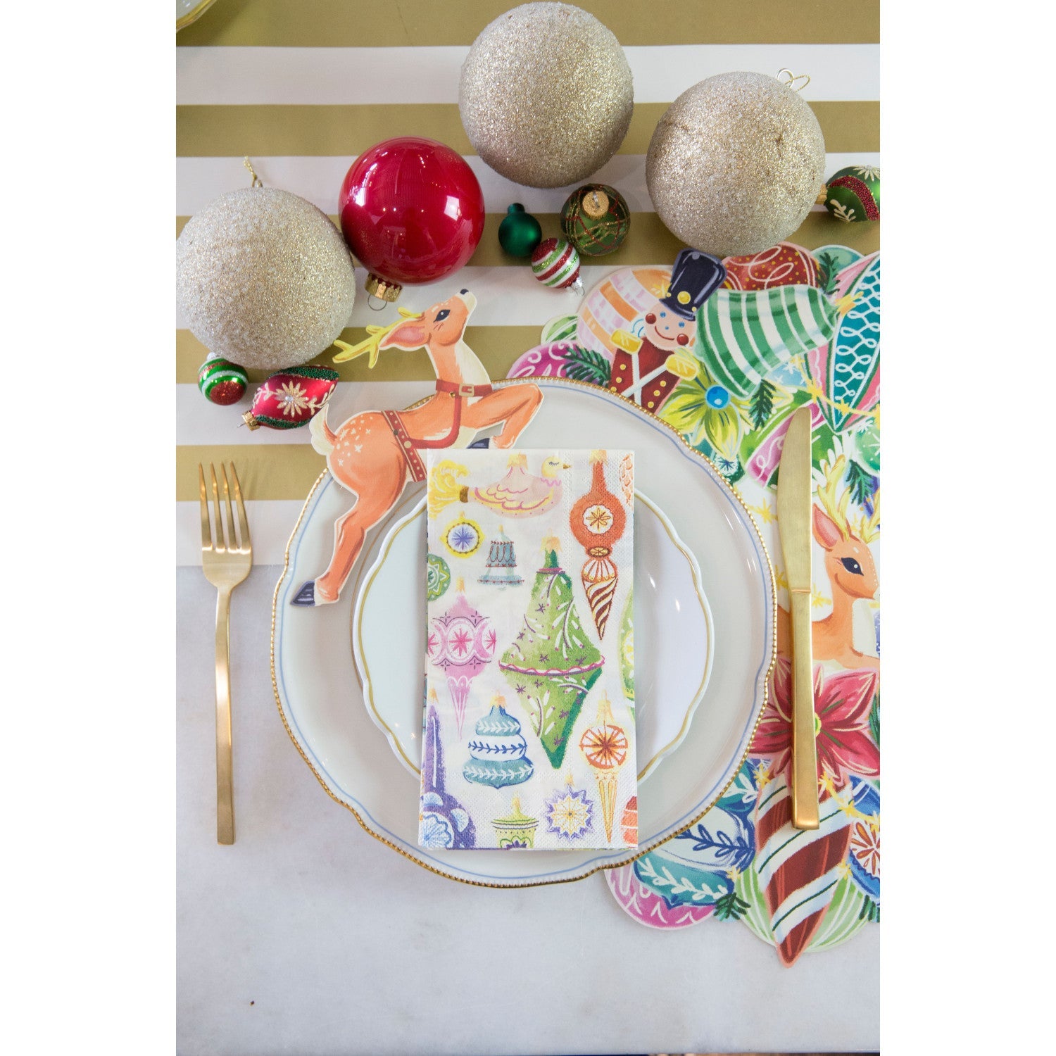 A festive Christmas place setting featuring an Ornament Guest napkin centered on the plate.