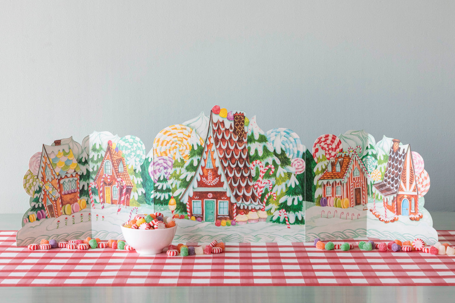 Colorful illustration of a whimsical, fantastical Gingerbread Centerscape village with intricately patterned buildings amidst lush greenery by Hester &amp; Cook.