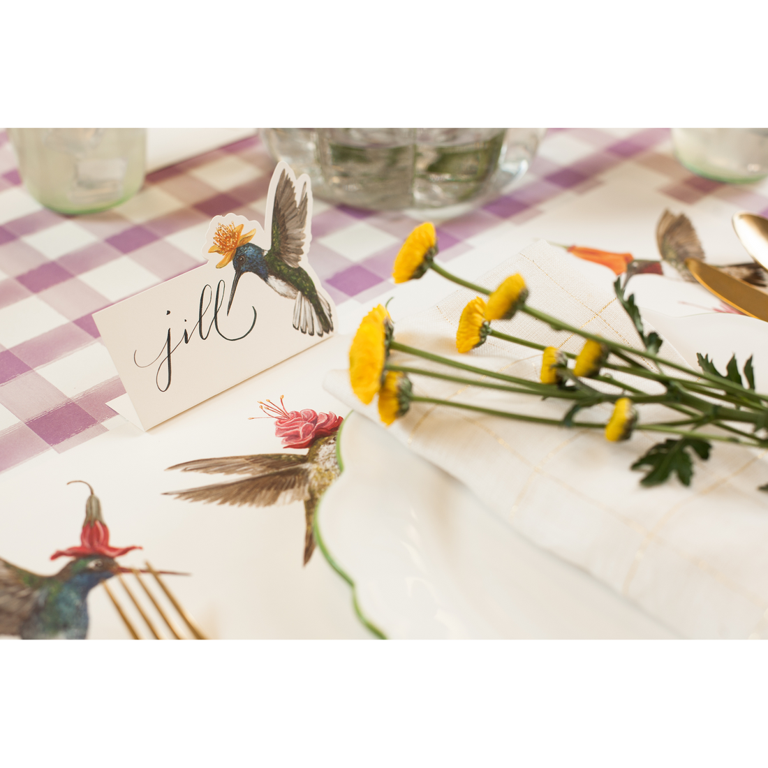 A Hummingbird Place Card labeled &quot;Jill&quot; standing on a tablescape next to a hummingbird placemat.