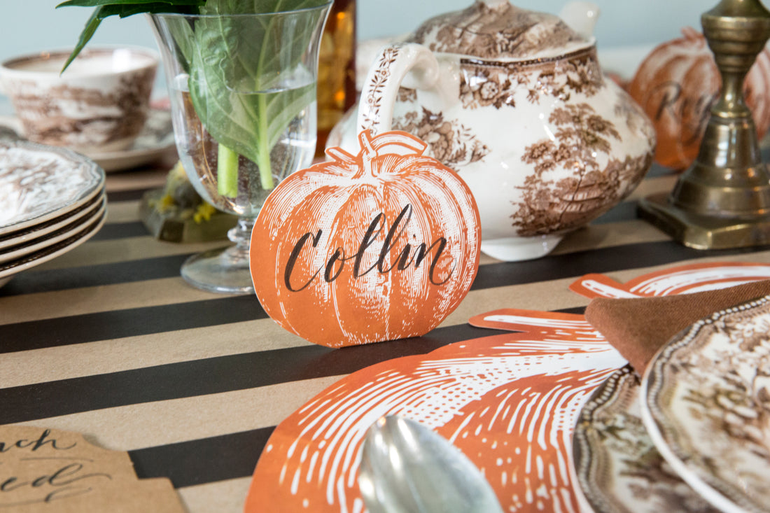 An elegant fall table setting featuring a Pumpkin Place Card labeled &quot;Collin&quot; standing behind a plate.