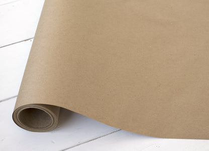 A roll of Basic Kraft Runner by Hester &amp; Cook, perfect for gift wrapping or as a rustic table runner on a wooden floor.