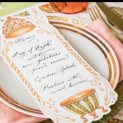 Close-up of an Exquisite Egg Table Card with a menu written on it in beautiful script resting on the plate of an elegant Easter place setting.