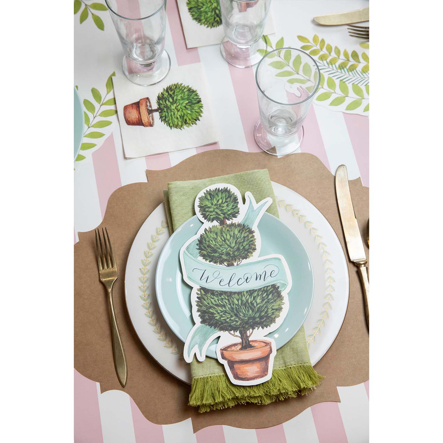 An elegant place setting featuring a Topiary Table Accent with &quot;Welcome&quot; written on the ribbon resting on the plate.