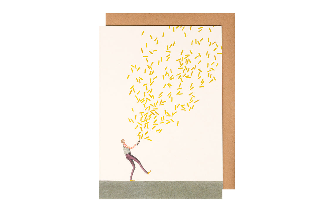 A greeting card featuring a stylized illustration of a man shooting a confetti cannon full of gold confetti over the white background, with the included kraft paper envelope.