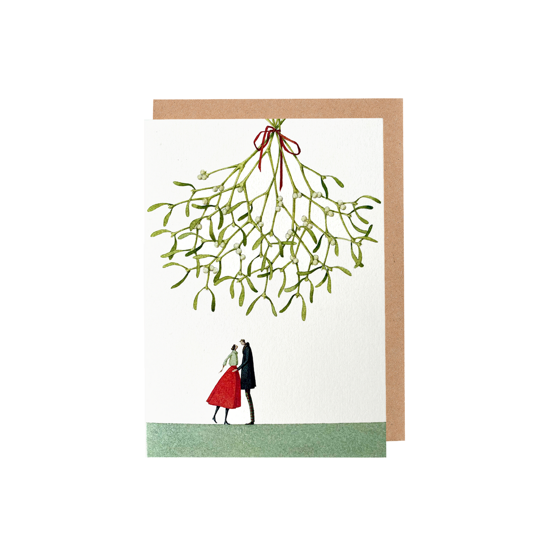 The Christmas Kiss Greeting Card featuring a watercolor illustration of a couple standing on a green field under a gigantic sprig of mistletoe hanging from above over a white background, with included brown kraft paper envelope.