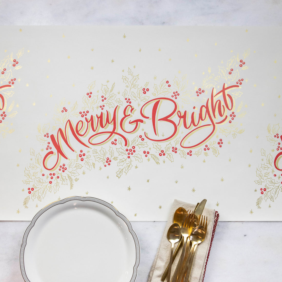 The Merry &amp; Bright Runner on a white table with a plate, napkin and cutlery.