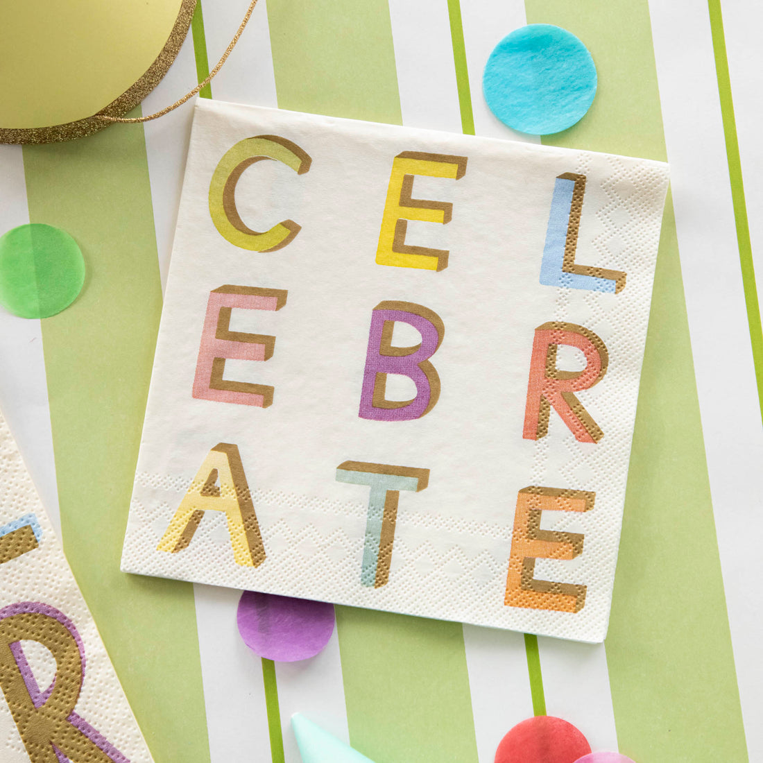 A Celebrate Cocktail Napkin on a festive table setting, from above.