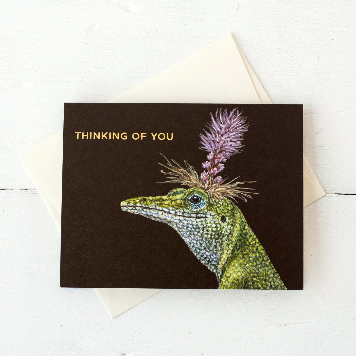 A Bella Lizard Card resting on a white table with the included off-white envelope tucked behind it. 