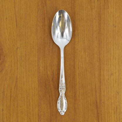 A Hester &amp; Cook vintage silver-plate serving spoon sits on top of a green napkin.