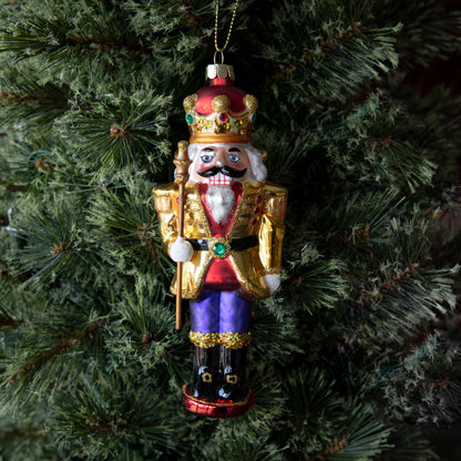 Glass Glitterville Nutcracker Ornaments on a mantle with Christmas decorations.