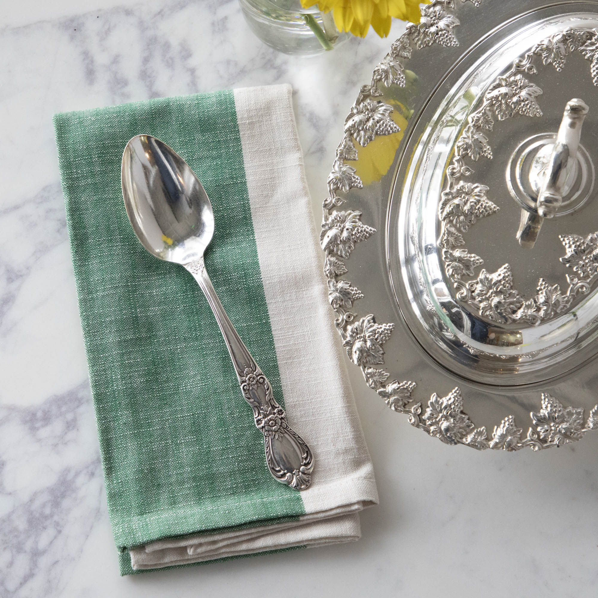 A Hester &amp; Cook vintage silver-plate serving spoon sits on top of a green napkin.