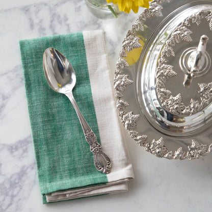 A Hester &amp; Cook vintage silver-plate serving spoon sits on top of a green napkin.