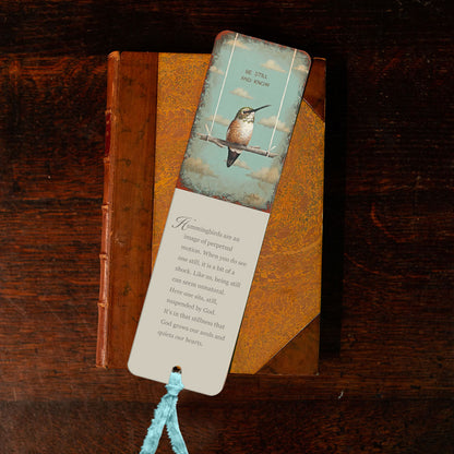 A David Arms bookmark with a hummingbird and a red ribbon.