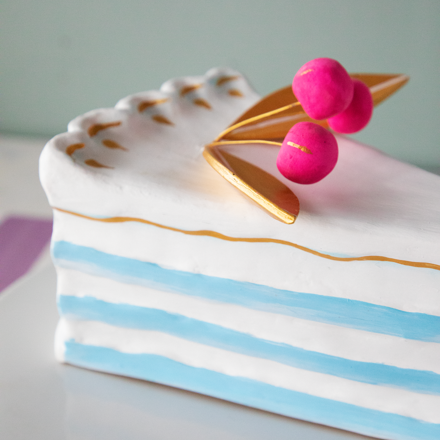 A stack of plates with Glitterville Large French Cake Slices with Gold Leaf on them for a party.